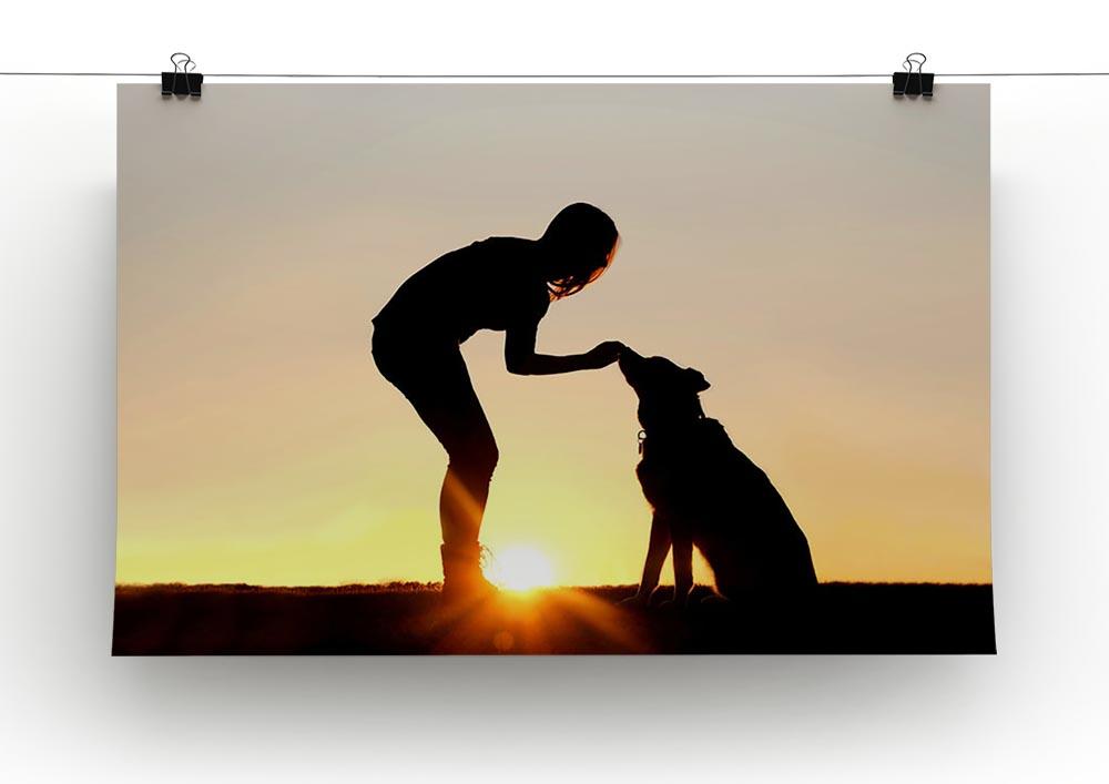 A silhouette of a girl sitting outside in the grass with her pet German Shepherd Mix Dog feeding him treats during training in front of a sunsetting sky. Canvas Print or Poster - Canvas Art Rocks - 2